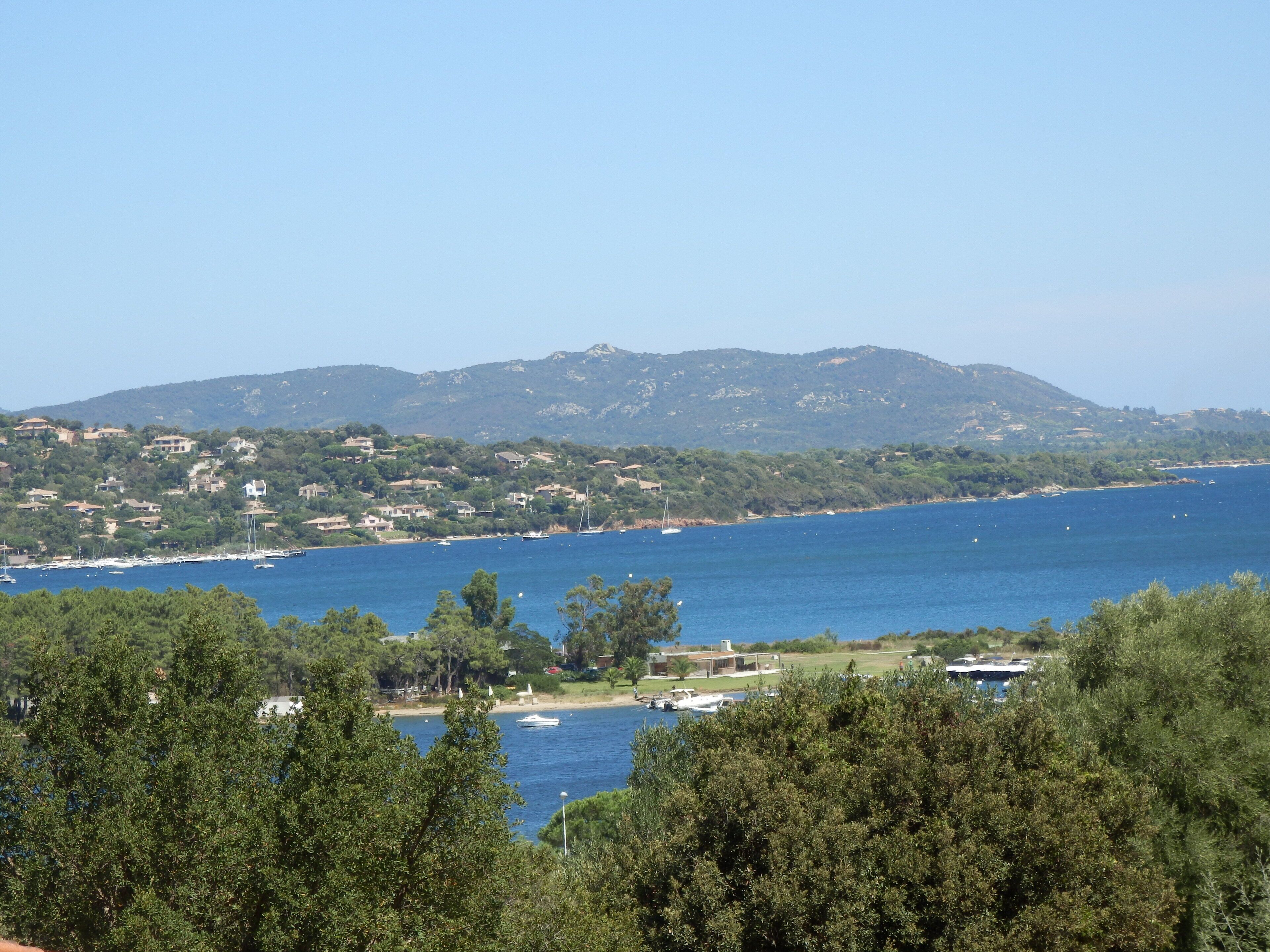Un borgo costiero con vista sul mare, case e colline sullo sfondo.