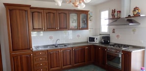 Una cocina con armarios de madera, microondas, estufa y fregadero.