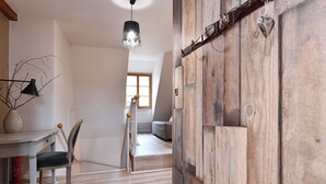 A room with a wooden door, a dining table with chairs, a hanging light fixture, and a view of another room with a bed. - Beraweka ***, Apartment for 4 to 6 people in the historic center of Colmar - 2 bedrooms, bathroom,... (Colmar)