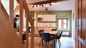 A modern kitchen with wooden cabinets, a dining table with chairs, and a staircase leading to an upper level. - Beraweka ***, Apartment for 4 to 6 people in the historic center of Colmar - 2 bedrooms, bathroom,... (Colmar)