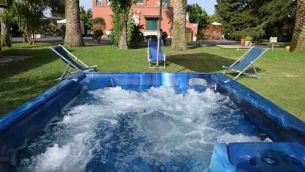 A hot tub with two lounge chairs and an umbrella in a garden setting. -  Pool, whirlpool, garden, internet WiFi close to Rome. Relax and rest. (Monte Migliore-la Selvotta)