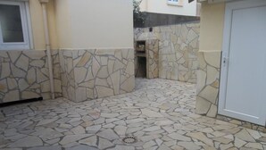 A courtyard with a stone floor and walls, a small brick oven, and a door. - For rent; villa in the center of a resort, quiet area in Valras Beach (Valras-Plage)