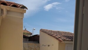 A stone-tiled patio with a white door and a beige wall. - For rent; villa in the center of a resort, quiet area in Valras Beach (Valras-Plage)