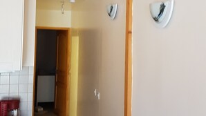 Cocina con armarios blancos, una silla de madera y un pasillo que conduce a otra habitación.