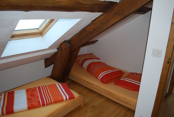 A small attic bedroom with two beds, wooden beams, a skylight, and a white door. - Part of an old manor with a large swimming pond at the border triangle B, NL, D (Gemmenich/Plombières)
