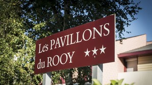 Une enseigne indiquant « Les Pavillons du Rooy », avec une vue dégagée sur la verdure environnante et le bâtiment en arrière-plan.