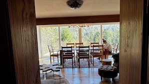 A wooden interior with a dining area, a sofa, and a dog.