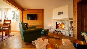 A cozy living room with a fireplace, wooden walls, and a green sofa.