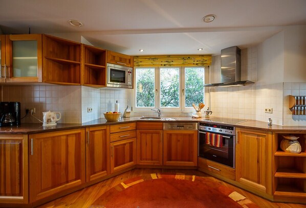 A modern kitchen with wooden cabinets, a microwave, an oven, and a dishwasher.