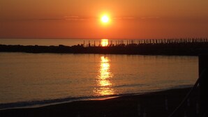 Un atardecer sobre un mar tranquilo con un muelle que se adentra en el agua.