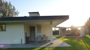 Una casa moderna con un porche cubierto, una puerta y un pequeño jardín.