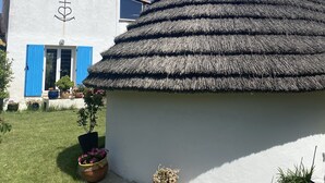A white building with a thatched roof and blue shutters.
