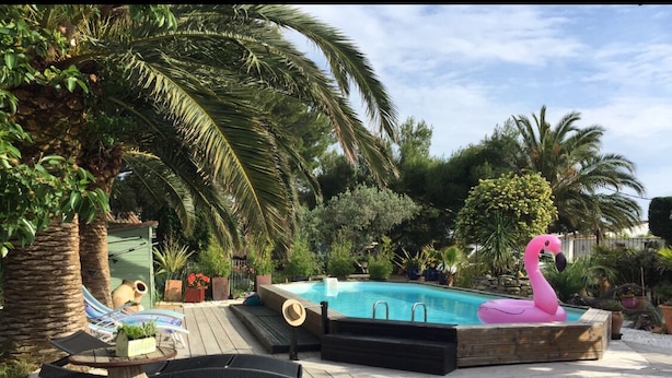 A wooden deck with a swimming pool, lounge chairs, and a pink flamingo statue.