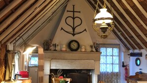 A rustic dining area with a wooden table and chairs, a fireplace, and a hanging light fixture.