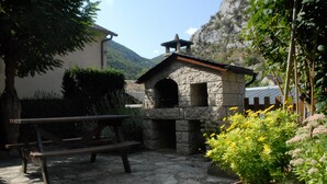 A stone building with a small archway, a wooden bench, and a potted plant with yellow flowers. - GITE IN THE HEART OF THE GORGES DU TARN (La Malène)