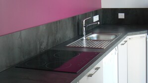 Una cocina moderna con una paleta de colores blanco y negro, horno empotrado y un lavamanos de acero inoxidable.