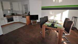A modern kitchen with white cabinets, a microwave, and a dining area with a table set for two.