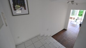 A hallway with a tiled floor, a framed abstract painting, and a view of a backyard through an open door.