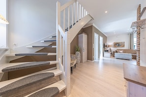 Un interior moderno con una escalera que lleva a una sala de estar, un sofá y un televisor.