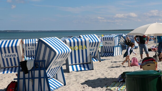 Strandstole med navne på, en klar himmel og havet i baggrunden.