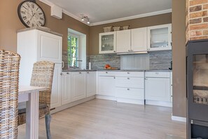 A kitchen with white cabinets, a built-in stove, and a large clock on the wall.