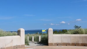 En sti der fører til en strand med et skilt og havudsigt.