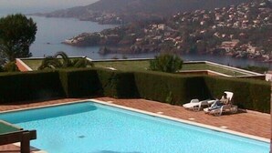Une piscine offrant une vue sur une ville côtière et sur une montagne en arrière-plan.