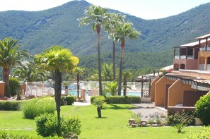 A resort with a pool, palm trees, and mountains in the background.