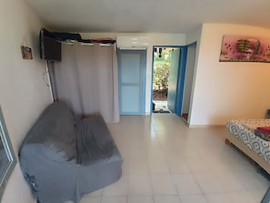 Una habitación con una cama, un televisor montado en la pared y una puerta que da a un espacio exterior.
