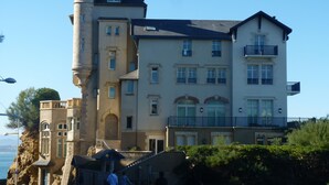 Un grand immeuble à étages, doté d’une tour et d’un balcon bien visibles.