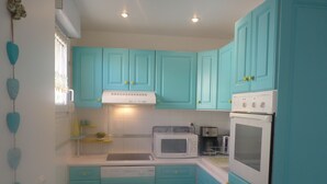 Une cuisine avec des meubles de couleur turquoise, un lave-vaisselle, un four à micro-ondes et un four traditionnel.