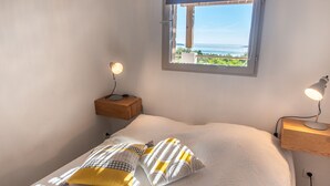 A bedroom with a bed, two bedside lamps, a window with a view, and a nightstand.