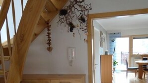 Een houten trap leidt naar een kamer met een betegelde vloer, een houten kast en een stoel.