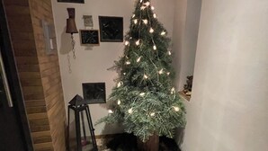 Een hoek van een gang met een kerstboom, een sterdcoratie en ingekaderde foto's aan de muur.
