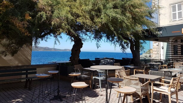 An outdoor seating area with tables and chairs, overlooking a body of water. - BEAUTIFUL APARTMENT IN RESIDENCE STANDING UP BEAUTIFUL SEA AND MOUNTAIN (L'île-Rousse)