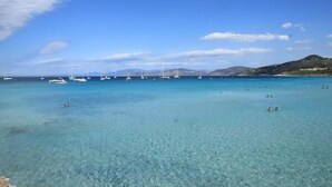 A coastal scene with clear turquoise waters, boats, and a hilly landscape in the background. - BEAUTIFUL APARTMENT IN RESIDENCE STANDING UP BEAUTIFUL SEA AND MOUNTAIN (L'île-Rousse)
