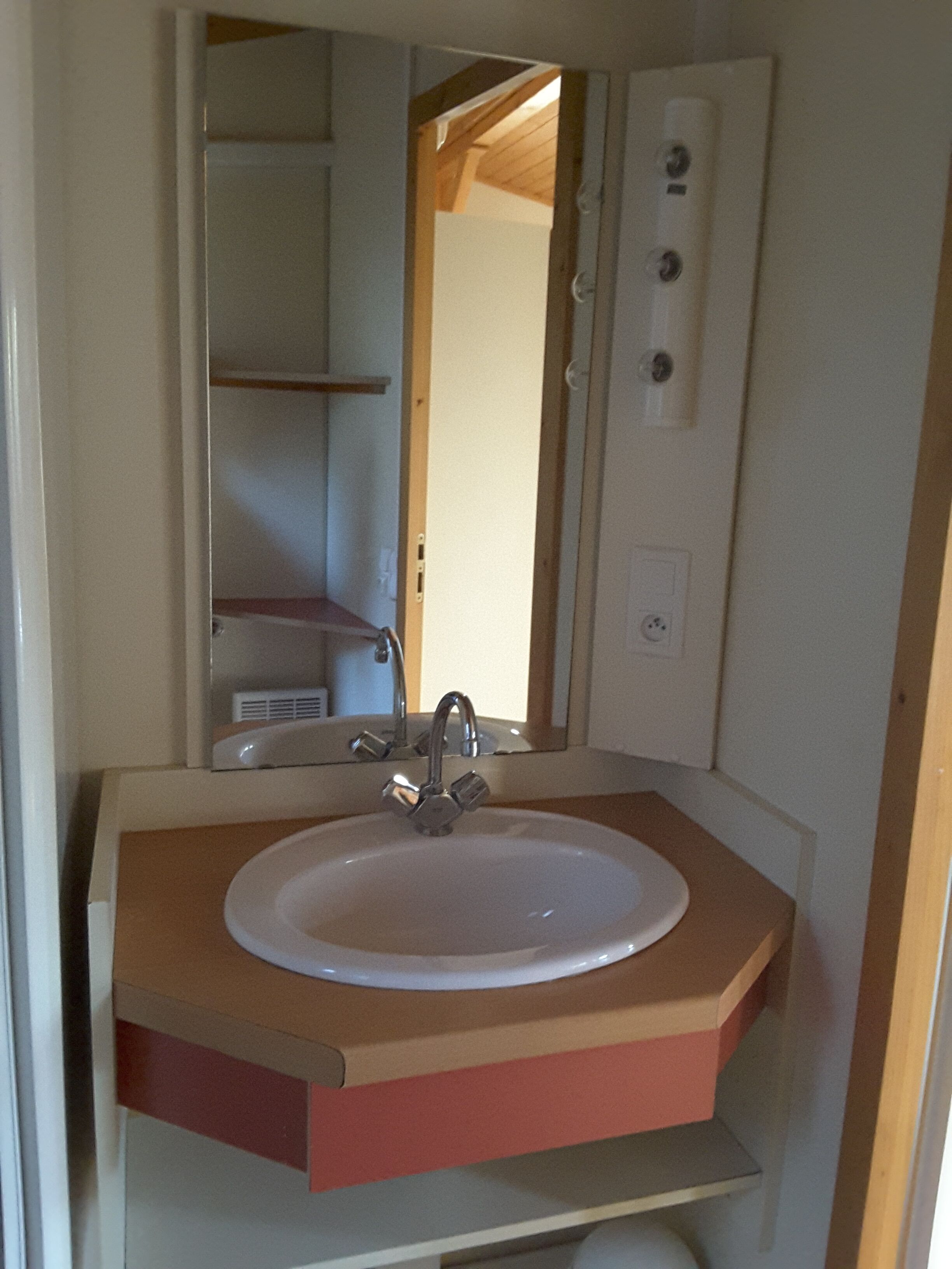 A bathroom with a white sink, a mirror, and a wooden door.