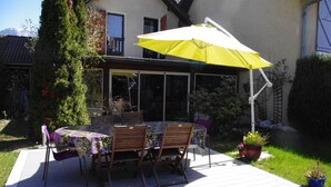 Un patio con una mesa, sillas, un paraguas amarillo y plantas en macetas.