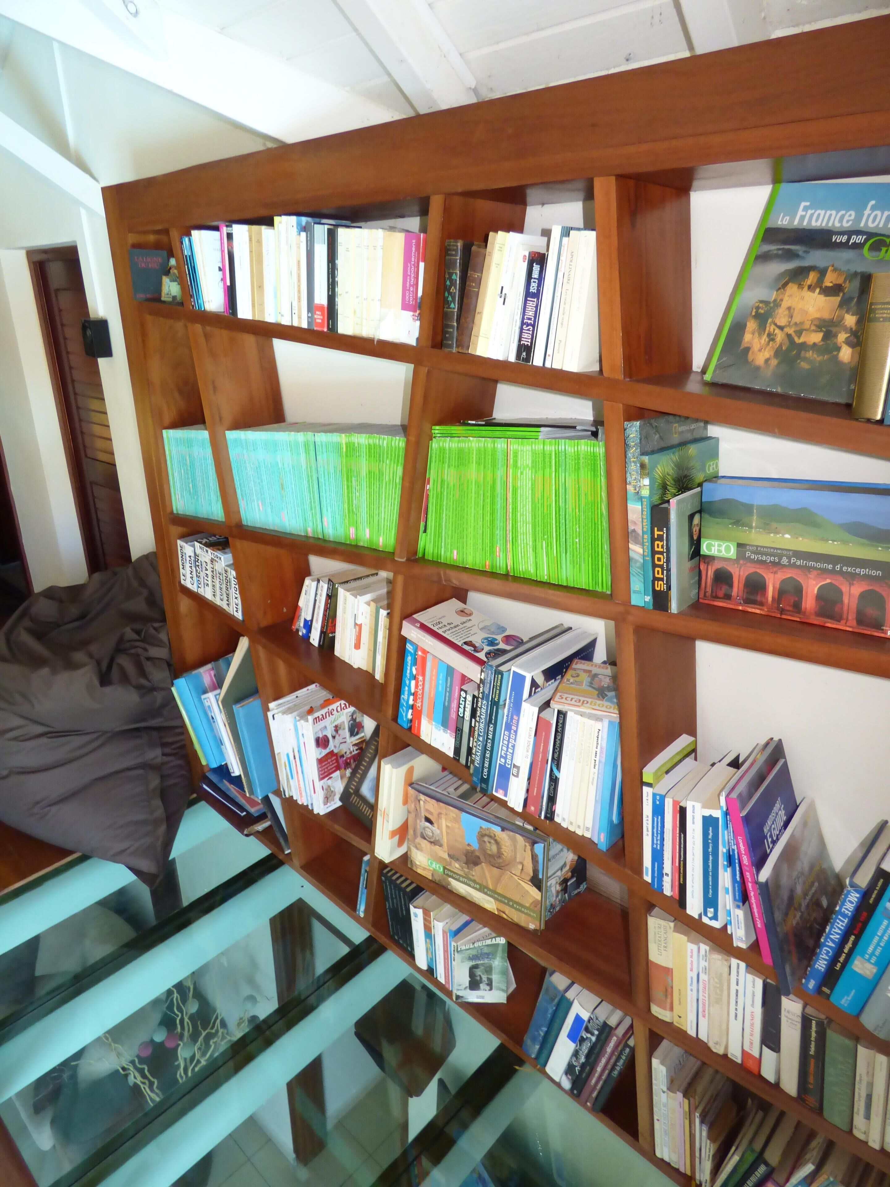 A bookshelf with various books and magazines, a glass display case, and a wooden shelf structure.