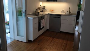 Moderni keittiö, jossa on valkoiset kaapit, ruostumattomasta teräksestä valmistettu uuni ja astianpesukone.
