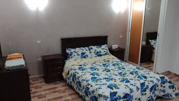 Un dormitorio con una cama, una mesita de noche, un aparador y un espejo.