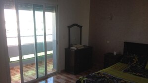 A bedroom with a bed, a dresser, a mirror, and a sliding glass door leading to a balcony. - Studio next to Macdonald center agdal (Rabat)