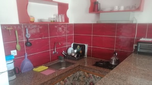 A kitchen with red tiles, a sink, a stove, and various utensils. - Studio next to Macdonald center agdal (Rabat)