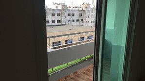 A view from a balcony with a metal railing, looking out over a cityscape with buildings and a clear sky. - Studio next to Macdonald center agdal (Rabat)