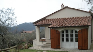 A house with a tiled roof, a wooden door, and a stone pathway leading to the entrance.