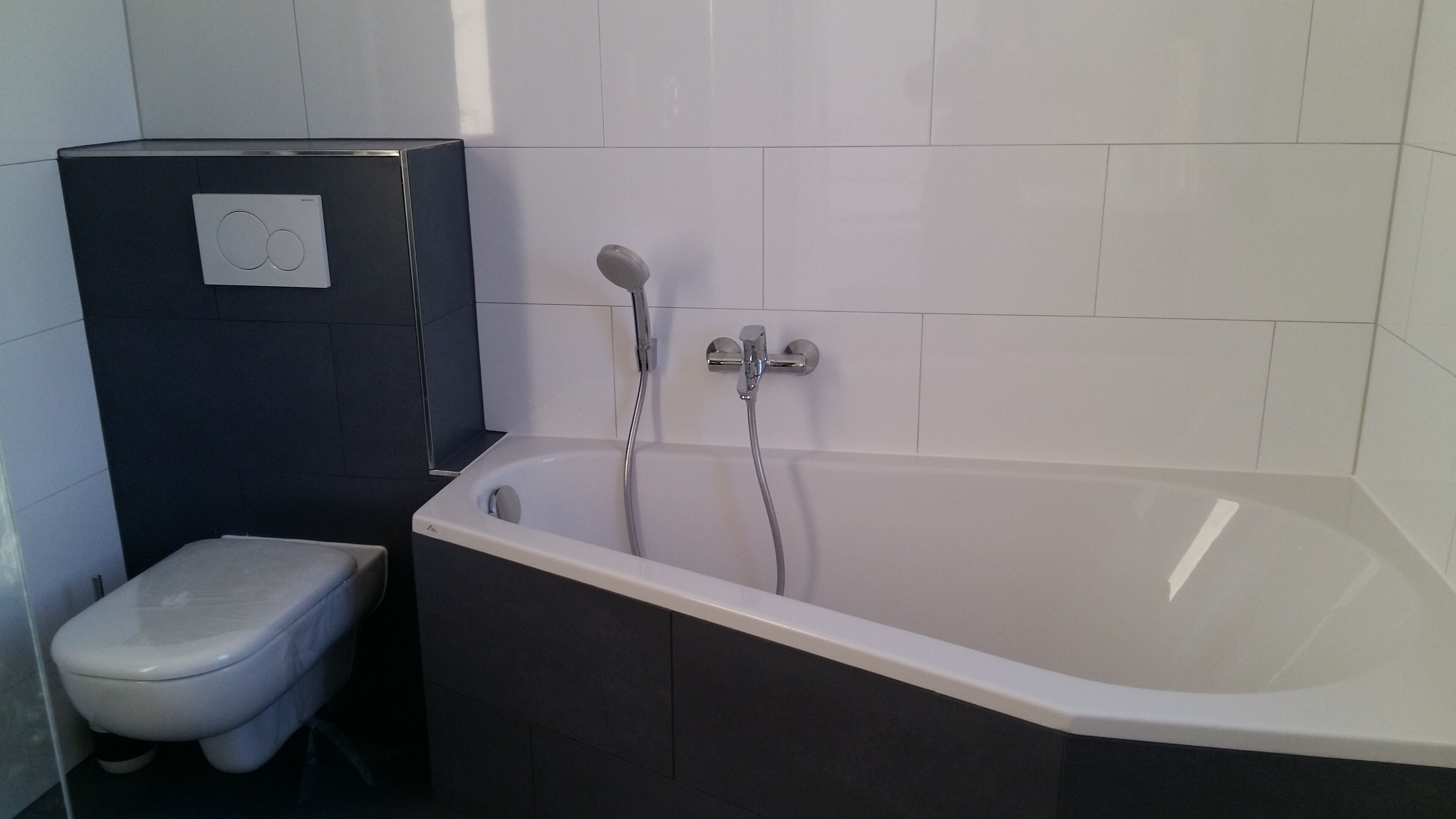 A bathroom with a bathtub, toilet, and a black cabinet.