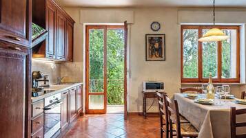 A kitchen with wooden cabinets, a dining table set for two, and a view of the outdoors through a glass door.