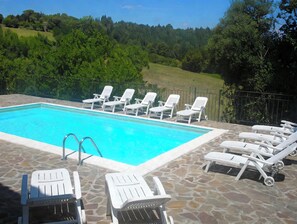 A rectangular swimming pool with a stone deck surrounding it.