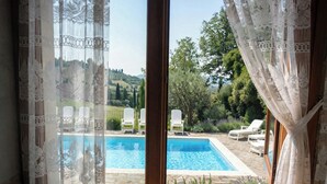 Ein Zimmer mit Blick auf einen Swimmingpool, weißen Vorhängen und einem Holzboden.