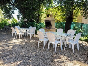 Un espace extérieur aménagé avec une table et des chaises, entouré d’arbres et d’une structure en pierre.